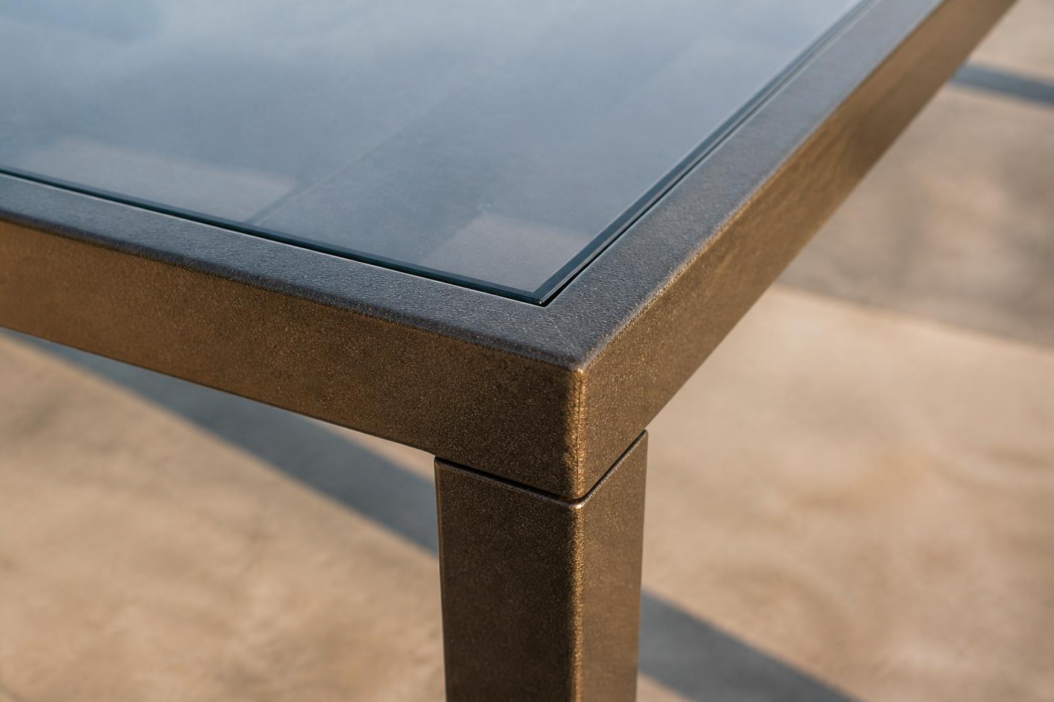 Close-up of an outdoor coffee table's glass top and aluminum frame joint