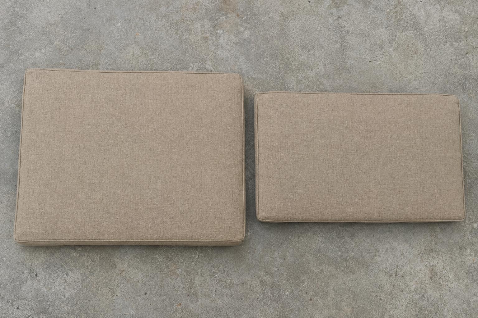 Separate tan outdoor seat and back cushions resting on a flat surface