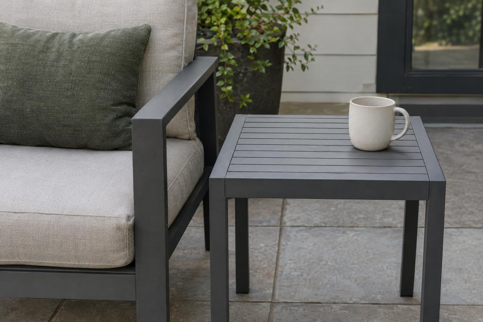 Outdoor side table beside a cushioned chair arm with clear floor space below